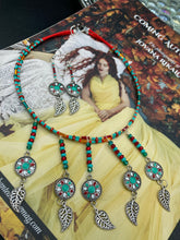 Load image into Gallery viewer, This two-strand adjustable necklace features a culturally inspired design with vibrant green turquoise, bright red, orange, green and gold glass beads, accompanied by silver plated feather charms that create a unique sense of motion. An ideal accessory for summer styles, this native tribal pattern necklace and matching earrings set will perfectly complete any ensemble.  Measurements:  Necklace: 15 3/4” adjustable up to 18" in length
