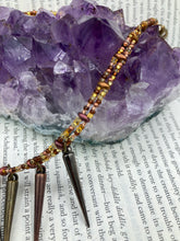 Load image into Gallery viewer, A copper-toned, adjustable Steampunk-style glass beaded necklace is detailed with sharp-drop metal plated hanging beads. Bright orange rectangular tube beads mix with other shapes for an eye-catching effect, while double-hole flat matte copper-toned beads provide a collar finish which makes this piece drape elegantly across the neck. A bold and sophisticated accessory.
