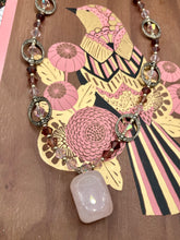 Load image into Gallery viewer, This exquisite necklace features a soft pink Rose Quartz pendant with multi-colored glass beads that transition from iridescent pink, to light purple and darker shades of purple. The sequence of beads complements the Rose Quartz pendant&#39;s delicate hue, and is accompanied with a set of subtly-styled matching earrings for a complete look.  Measurements:   Necklace is 16 1/2”
