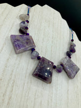 Load image into Gallery viewer, This necklace features large trapezoid-shaped Amethyst pendants and small Amethyst nuggets strung together with shimmery multicolored glass beads, creating a unique and eye-catching statement piece.  Measurements:  Necklace is is 15 1/2” adjustable up to 17&quot;
