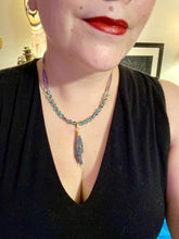 Load image into Gallery viewer, This necklace boasts a stunning Rainbow Kyanite wired stone pendant and two strands of shimmering glass beads. The blues contain hues of pink, gold, blue and green, offering a vibrant and bold addition to any jewelry collection.  Measurements:  Necklace is 17” in length, can be adjusted to 18&quot;
