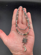 Load image into Gallery viewer, This Dainty Smiling Crescent Moon And Star Silver And Gray Choker Style Necklace features a variety of shimmering glass beads in light silver and gray tones. Varying in shape and size, these beads lend a unique and witchy celestial vibe to the necklace.  Measurements:  Necklace is 15 3/4”adjustable up to 18&quot;
