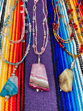 Load image into Gallery viewer, This large agate pendant features a variety of pink hues, from light to dark, and is accompanied by two strands of glass beaded necklaces with pink, silver, gold, and clear beads. The combination of colors creates a stunning and vibrant look, perfect for accessorizing any summer look.  Measurements:  Necklace is 15” adjustable up to 18&quot; in length 
