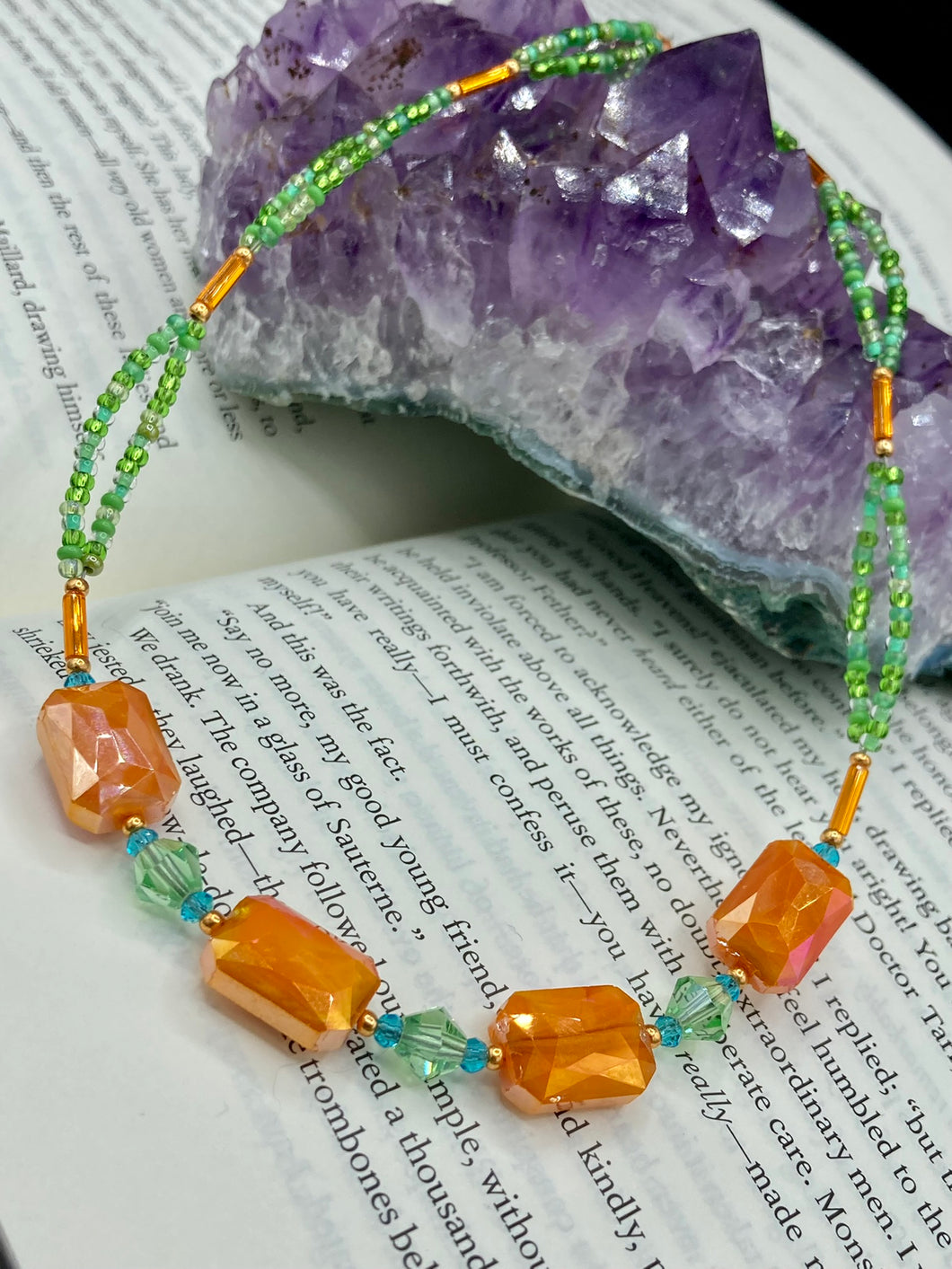 This unique, double-strand necklace consists of a blend of glass beads, including multi-green and rectangular, faceted orange glass beads, and is accented with gold and light blue elements. The vibrant combination is perfect for any summer look and will enhance any outfit.  Measurements:  Necklace is 16” and can be adjusted up to 18