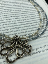 Load image into Gallery viewer, This stylish necklace features a silver plated metal octopus pendant and vibrant iridescent and silver-gray glass beads of various sizes. The Steampunk-inspired design provides a textured, patterned and voluminous look perfect for any dark goth or witchy aesthetic. Measurements:  Necklace measures 15 1/2” adjustable up to 17” in length
