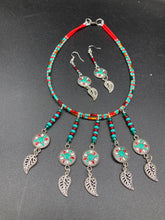 Load image into Gallery viewer, This two-strand adjustable necklace features a culturally inspired design with vibrant green turquoise, bright red, orange, green and gold glass beads, accompanied by silver plated feather charms that create a unique sense of motion. An ideal accessory for summer styles, this native tribal pattern necklace and matching earrings set will perfectly complete any ensemble.  Measurements:  Necklace: 15 3/4” adjustable up to 18" in length
