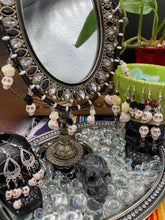 Load image into Gallery viewer, This sophisticated, yet dark-themed necklace utilizes small howlite skull beads along with black and white quartize floral beads to capture the iconic floral crown of Frida Kahlo. This Chingona, Cabrona, Latina Chicana, Goth, Vampire Goth, Dark Witchy Style jewelry can be used to inspire and to celebrate Dia de los Muertos. Equally suitable for dressy and casual outfits, the piece gives a unique edge to any look.
