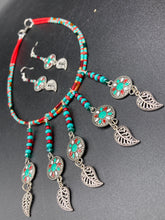 Load image into Gallery viewer, This two-strand adjustable necklace features a culturally inspired design with vibrant green turquoise, bright red, orange, green and gold glass beads, accompanied by silver plated feather charms that create a unique sense of motion. An ideal accessory for summer styles, this native tribal pattern necklace and matching earrings set will perfectly complete any ensemble.  Measurements:  Necklace: 15 3/4” adjustable up to 18" in length
