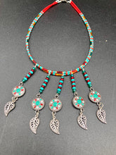 Load image into Gallery viewer, This two-strand adjustable necklace features a culturally inspired design with vibrant green turquoise, bright red, orange, green and gold glass beads, accompanied by silver plated feather charms that create a unique sense of motion. An ideal accessory for summer styles, this native tribal pattern necklace and matching earrings set will perfectly complete any ensemble.  Measurements:  Necklace: 15 3/4” adjustable up to 18" in length
