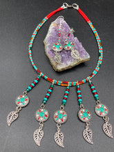 Load image into Gallery viewer, This two-strand adjustable necklace features a culturally inspired design with vibrant green turquoise, bright red, orange, green and gold glass beads, accompanied by silver plated feather charms that create a unique sense of motion. An ideal accessory for summer styles, this native tribal pattern necklace and matching earrings set will perfectly complete any ensemble.  Measurements:  Necklace: 15 3/4” adjustable up to 18" in length
