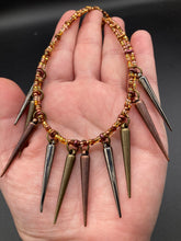 Load image into Gallery viewer, A copper-toned, adjustable Steampunk-style glass beaded necklace is detailed with sharp-drop metal plated hanging beads. Bright orange rectangular tube beads mix with other shapes for an eye-catching effect, while double-hole flat matte copper-toned beads provide a collar finish which makes this piece drape elegantly across the neck. A bold and sophisticated accessory.
