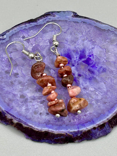 These earrings feature a single strand constructed with natural rhodonite stone chips and delicate pink glass beads for a unique, nature-inspired look. Measurements: 1 1/2