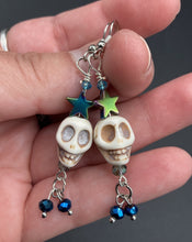 Load image into Gallery viewer, Mini Howlite Skull Bead Earrings, Stardust Galaxy Cosmos large star shaped rainbow hematite beads and light blue glass bead for a pastel goth vibe. Two small dark blue glass beads on the bottom to add some movement. Perfect for a witch, goth, or day of the dead outfit. You can dress these up or down, it will definitely give your outfit a unique look.   Measurements: 2 ” in length
