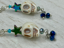 Load image into Gallery viewer, Mini Howlite Skull Bead Earrings, Stardust Galaxy Cosmos large star shaped rainbow hematite beads and light blue glass bead for a pastel goth vibe. Two small dark blue glass beads on the bottom to add some movement. Perfect for a witch, goth, or day of the dead outfit. You can dress these up or down, it will definitely give your outfit a unique look.   Measurements: 2 ” in length

