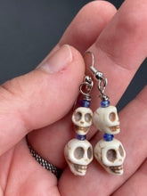 Load image into Gallery viewer, Mini Howlite Skull Bead Earrings, two tiny skull bead stacked set of earrings with shimmery blue glass beads in between each skull to give these cuties some sparkle. Perfect for any goth, emo, witchy, day of the dead outfit. You can dress these up or down, it will definitely give your outfit a unique look.  Measurements: 1 ” in length
