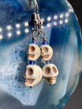 Load image into Gallery viewer, Mini Howlite Skull Bead Earrings, two tiny skull bead stacked set of earrings with shimmery blue glass beads in between each skull to give these cuties some sparkle. Perfect for any goth, emo, witchy, day of the dead outfit. You can dress these up or down, it will definitely give your outfit a unique look.  Measurements: 1 ” in length

