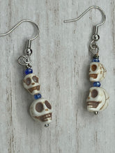 Load image into Gallery viewer, Mini Howlite Skull Bead Earrings, two tiny skull bead stacked set of earrings with shimmery blue glass beads in between each skull to give these cuties some sparkle. Perfect for any goth, emo, witchy, day of the dead outfit. You can dress these up or down, it will definitely give your outfit a unique look.  Measurements: 1 ” in length
