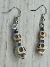 Load image into Gallery viewer, Mini Howlite Skull Bead Earrings, two tiny skull bead stacked set of earrings with shimmery blue glass beads in between each skull to give these cuties some sparkle. Perfect for any goth, emo, witchy, day of the dead outfit. You can dress these up or down, it will definitely give your outfit a unique look.  Measurements: 1 ” in length
