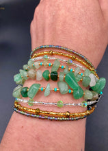 Load image into Gallery viewer, This Bohemian, Hippie Natural Genuine Stone Bracelet is composed of nine strands of shimmery multi-color glass beads and natural green aventurine chip stones. This striking, nature-inspired style showcases a vibrant blend of gold, silver, green, and turquoise beads, with a range of sizes, including both large and small round beads.   Measurements:  Bracelet: 8 1/4&quot; in length
