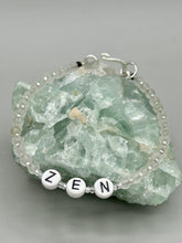 Load image into Gallery viewer, Hand beaded bracelet with clear and silver glass beads, Zen letters Metal wire with hook-eye clasp.
