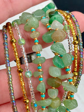 Load image into Gallery viewer, This Bohemian, Hippie Natural Genuine Stone Bracelet is composed of nine strands of shimmery multi-color glass beads and natural green aventurine chip stones. This striking, nature-inspired style showcases a vibrant blend of gold, silver, green, and turquoise beads, with a range of sizes, including both large and small round beads.   Measurements:  Bracelet: 8 1/4&quot; in length

