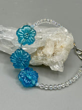 Load image into Gallery viewer, This light blue pressed glass floral bracelet is a sophisticated addition to any summer look. Its iridescent shimmer finish adds a classy touch to its intricate metal wire and lobster claw clasp. Perfect for any nature-inspired wardrobe. Measurements:  Bracelet: 8&quot; in length 
