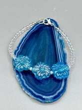 Load image into Gallery viewer, This light blue pressed glass floral bracelet is a sophisticated addition to any summer look. Its iridescent shimmer finish adds a classy touch to its intricate metal wire and lobster claw clasp. Perfect for any nature-inspired wardrobe. Measurements:  Bracelet: 8&quot; in length 
