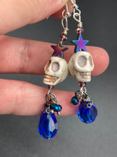Load image into Gallery viewer, Mini Howlite Skull Bead Earrings large star shaped rainbow hematite bead with a large bright blue teardrop shaped glass bead on the bottom of the skull for max shimmer and movement. Ultimate Chingona, Cabrona, Latina Chicana, Goth, Vampire Goth, Dark Witchy, La Bruja Style. You can dress these up or down, it will definitely give your outfit a unique look. You can dress these up or down, it will definitely give your outfit a unique look.  Measurements: 2 ” in length

