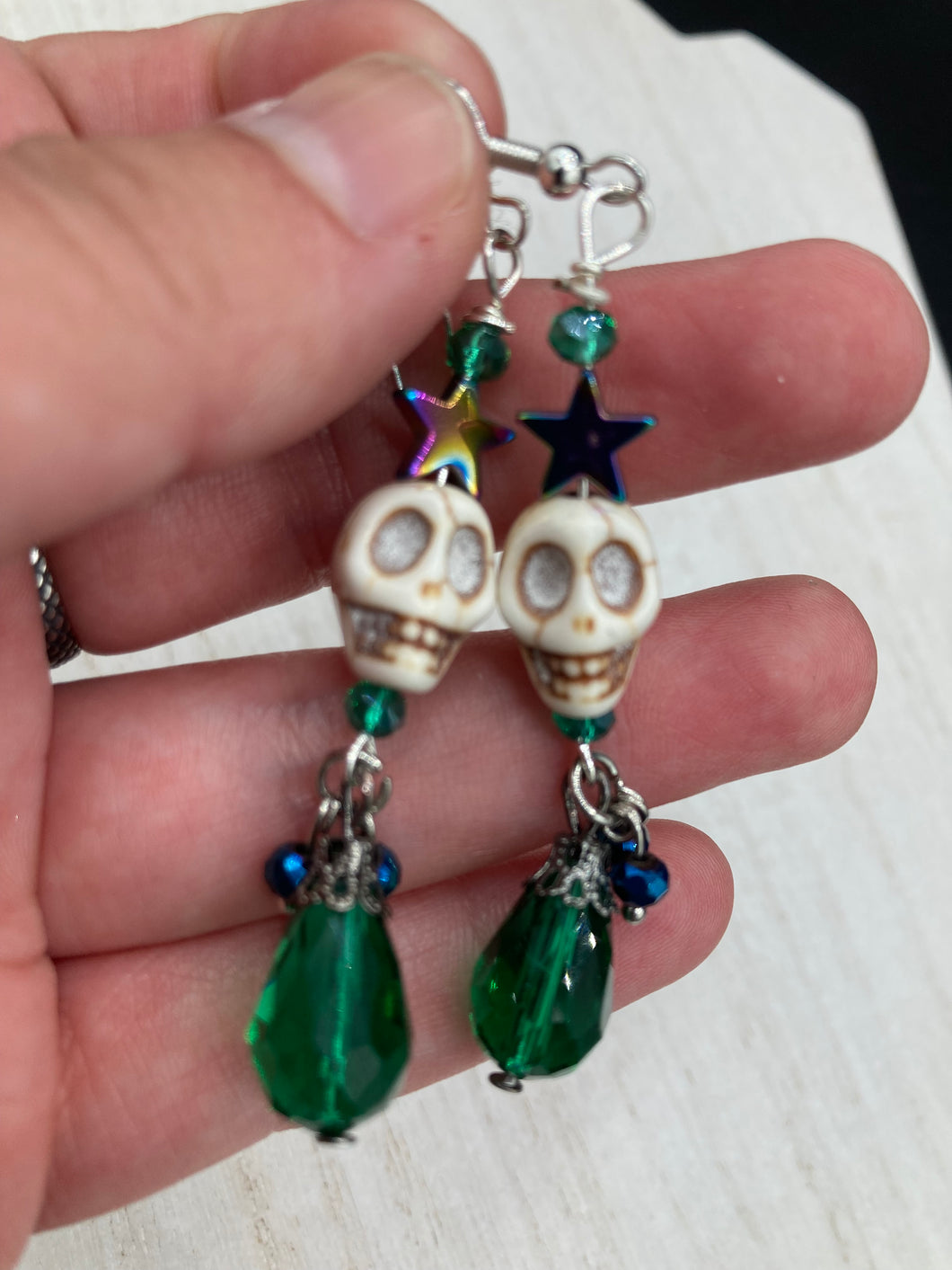 Mini Howlite Skull Bead Earrings large star shaped rainbow hematite bead with a large bright green teardrop shaped glass bead on the bottom of the skull for max shimmer and movement. Ultimate Chingona, Cabrona, Latina Chicana, Goth, Vampire Goth, Dark Witchy, La Bruja Style. You can dress these up or down, it will definitely give your outfit a unique look. You can dress these up or down, it will definitely give your outfit a unique look.  Measurements: 2 ” in length