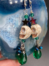 Load image into Gallery viewer, Mini Howlite Skull Bead Earrings large star shaped rainbow hematite bead with a large bright green teardrop shaped glass bead on the bottom of the skull for max shimmer and movement. Ultimate Chingona, Cabrona, Latina Chicana, Goth, Vampire Goth, Dark Witchy, La Bruja Style. You can dress these up or down, it will definitely give your outfit a unique look. You can dress these up or down, it will definitely give your outfit a unique look.  Measurements: 2 ” in length
