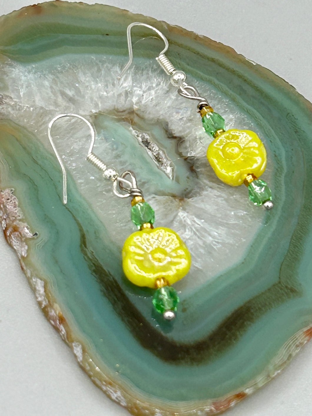 This delicate jewelry displays an array of gentle hues, vibrant yet soft.This light yellow pressed glass floral beaded bracelet and earrings set features an iridescent shimmer finish and is crafted with metal wire and a lobster claw clasp for easy closure. Measurements:  Bracelet: 8 1/2