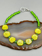 Load image into Gallery viewer, This delicate jewelry displays an array of gentle hues, vibrant yet soft.This light yellow pressed glass floral beaded bracelet and earrings set features an iridescent shimmer finish and is crafted with metal wire and a lobster claw clasp for easy closure. Measurements:  Bracelet: 8 1/2&quot; in length   Earrings: 1 1/4&quot; length
