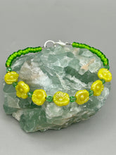 Load image into Gallery viewer, This delicate jewelry displays an array of gentle hues, vibrant yet soft.This light yellow pressed glass floral beaded bracelet and earrings set features an iridescent shimmer finish and is crafted with metal wire and a lobster claw clasp for easy closure. Measurements:  Bracelet: 8 1/2&quot; in length   Earrings: 1 1/4&quot; length
