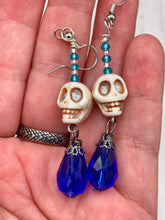 Load image into Gallery viewer, Mini Howlite Skull Bead Earrings and large bright blue teardrop shaped glass bead for major shimmery movement. Ultimate Chingona, Cabrona, Latina Chicana, Goth, Vampire Goth, Dark Witchy, La Bruja Style. You can dress these up or down, it will definitely give your outfit a unique look.   Measurements: 2 ” in length
