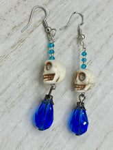 Load image into Gallery viewer, Mini Howlite Skull Bead Earrings and large bright blue teardrop shaped glass bead for major shimmery movement. Ultimate Chingona, Cabrona, Latina Chicana, Goth, Vampire Goth, Dark Witchy, La Bruja Style. You can dress these up or down, it will definitely give your outfit a unique look.   Measurements: 2 ” in length
