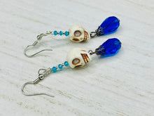 Load image into Gallery viewer, Mini Howlite Skull Bead Earrings and large bright blue teardrop shaped glass bead for major shimmery movement. Ultimate Chingona, Cabrona, Latina Chicana, Goth, Vampire Goth, Dark Witchy, La Bruja Style. You can dress these up or down, it will definitely give your outfit a unique look.   Measurements: 2 ” in length
