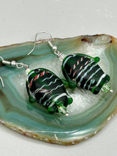 Load image into Gallery viewer, These nature-inspired glass fish earrings are the perfect addition to your boho look. Featuring a delightful dark green hue, the large puffy fish will bring a hippie vibe to your style. Measurements: 1 1/2” in length
