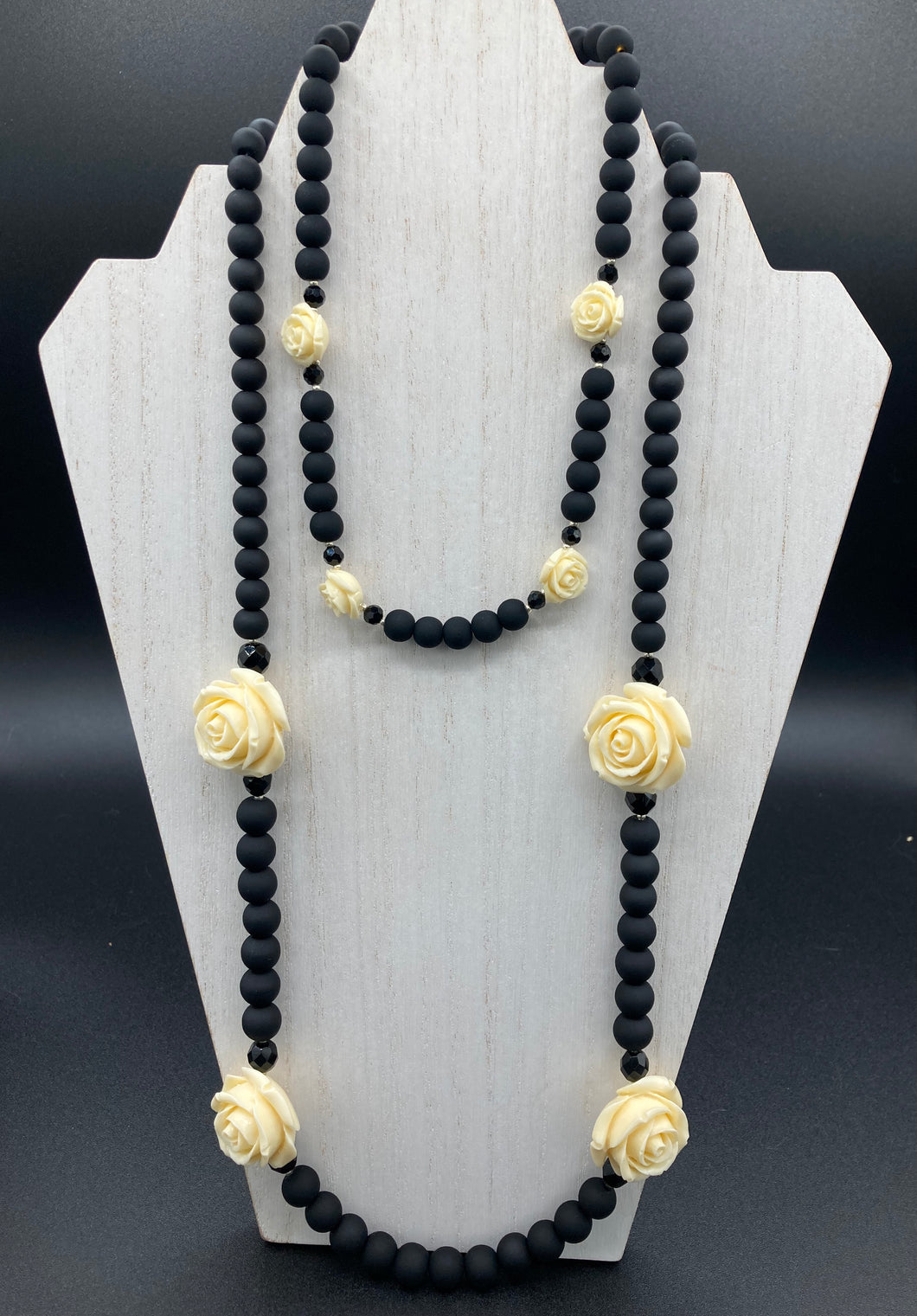 This Cocktail Chic Long Beaded Necklace is a unique piece that can be styled in different ways. Crafted with black flat matte glass beads for a luxurious look, the necklace is complemented by small and large white rose beads for contrast. The intricate petal details give the piece an extra special touch. This set is a simple and elegant pieces, very versatile looks and comes with a pair of matching earrings. Perfect cocktail chic attire, fancy wedding necklace, a minimalist look.