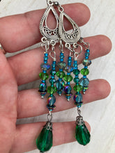 Load image into Gallery viewer, This Whimsical Blue Green Peacock Inspired Beaded Earrings set features bold chandelier style earrings with three long strands of glass bead. These show-stopping pieces boast a range of shimmering shades of blue, green, purple, and gold. A perfect addition to any fashionista&#39;s collection. Measurements: 3 1/2” in length
