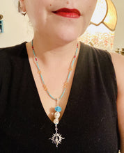 Load image into Gallery viewer, Enchanting Southwest Style Jewelry. Necklace captures Frida Kahlo&#39;s signature floral crown on her head. Howlite skull beads topped with turquoise quartize floral beads, style to represent mother and child. Dangling shimmery sun charm pendant to incorporated some movement. Chingona, Cabrona, Latina Chicana, Goth, Vampire Goth, Dark Witchy Style. This piece of jewelry can be worn for inspiration or a great Dia De Los Muertos jewelry piece. Necklace is 20” in length - flower, skull, and sun pendant is 3”
