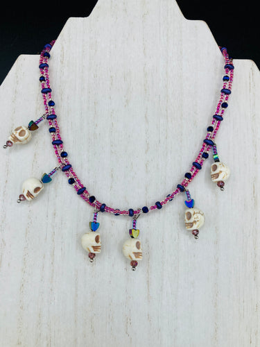 Dark gothic, elegant, and romantic necklace contains two beaded strands of pink beads that contain a dash of purple, blue, and gold hues. Tiny skull howlite skulls with rainbow hematite heart shaped beads to give this necklace a cute and romantic style. Comes with matching earrings. Necklace is 14”adjustable up to 18