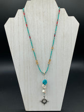 Load image into Gallery viewer, Enchanting Southwest Style Jewelry. Necklace captures Frida Kahlo&#39;s signature floral crown on her head. Howlite skull beads topped with turquoise quartize floral beads, style to represent mother and child. Dangling shimmery sun charm pendant to incorporated some movement. Chingona, Cabrona, Latina Chicana, Goth, Vampire Goth, Dark Witchy Style. This piece of jewelry can be worn for inspiration or a great Dia De Los Muertos jewelry piece. Necklace is 20” in length - flower, skull, and sun pendant is 3”
