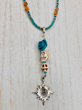 Load image into Gallery viewer, Enchanting Southwest Style Jewelry. Necklace captures Frida Kahlo&#39;s signature floral crown on her head. Howlite skull beads topped with turquoise quartize floral beads, style to represent mother and child. Dangling shimmery sun charm pendant to incorporated some movement. Chingona, Cabrona, Latina Chicana, Goth, Vampire Goth, Dark Witchy Style. This piece of jewelry can be worn for inspiration or a great Dia De Los Muertos jewelry piece. Necklace is 20” in length - flower, skull, and sun pendant is 3”
