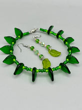 Load image into Gallery viewer, Long strand of glittering light green and gold glass beads, as well as a leaf-shaped glass charm at the bottom, combine to create a highly dynamic effect. These versatile earrings, perfect for a whimsical fairy princess, good witch, or nature-loving hippie look, draw on nature-inspired designs, providing the ideal finishing touch to any ensemble.  Measurements: 2 1/4” in length
