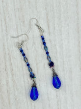 Load image into Gallery viewer, This stunning, one of a kind pair of celestial beaded earrings is a bold addition to any jewelry collection. Crafted with vibrant blue glass beads, the color contains varied shades of blue, purple, and hints of gold to create unique texture. The design is inspired by the awe-inspiring beauty of the majestic galaxy.  Measurements: 2 3/4 ” in length
