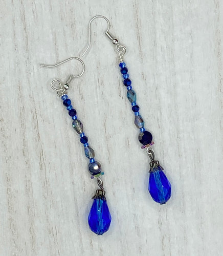 This stunning, one of a kind pair of celestial beaded earrings is a bold addition to any jewelry collection. Crafted with vibrant blue glass beads, the color contains varied shades of blue, purple, and hints of gold to create unique texture. The design is inspired by the awe-inspiring beauty of the majestic galaxy.  Measurements: 2 3/4 ” in length