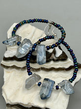 Load image into Gallery viewer, These ultra-trendy crystal nugget and glass beaded hoop earrings are perfect for any hippie or bohemian look. The dark blue glass beads give off an iridescent shimmer and blend brilliantly with the luster blue crystals, creating an eye catching contrast and a unique touch of nature-inspired beauty. Measurements: 2 1/4&quot; length

