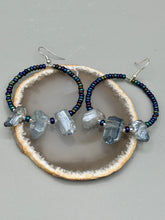 Load image into Gallery viewer, These ultra-trendy crystal nugget and glass beaded hoop earrings are perfect for any hippie or bohemian look. The dark blue glass beads give off an iridescent shimmer and blend brilliantly with the luster blue crystals, creating an eye catching contrast and a unique touch of nature-inspired beauty. Measurements: 2 1/4&quot; length
