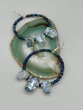 Load image into Gallery viewer, These ultra-trendy crystal nugget and glass beaded hoop earrings are perfect for any hippie or bohemian look. The dark blue glass beads give off an iridescent shimmer and blend brilliantly with the luster blue crystals, creating an eye catching contrast and a unique touch of nature-inspired beauty. Measurements: 2 1/4&quot; length
