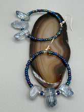 Load image into Gallery viewer, These ultra-trendy crystal nugget and glass beaded hoop earrings are perfect for any hippie or bohemian look. The dark blue glass beads give off an iridescent shimmer and blend brilliantly with the luster blue crystals, creating an eye catching contrast and a unique touch of nature-inspired beauty. Measurements: 2 1/4&quot; length
